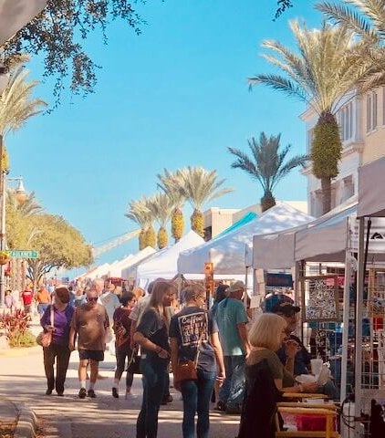 people shopping along Flagler Ave where there are vendors lined up 