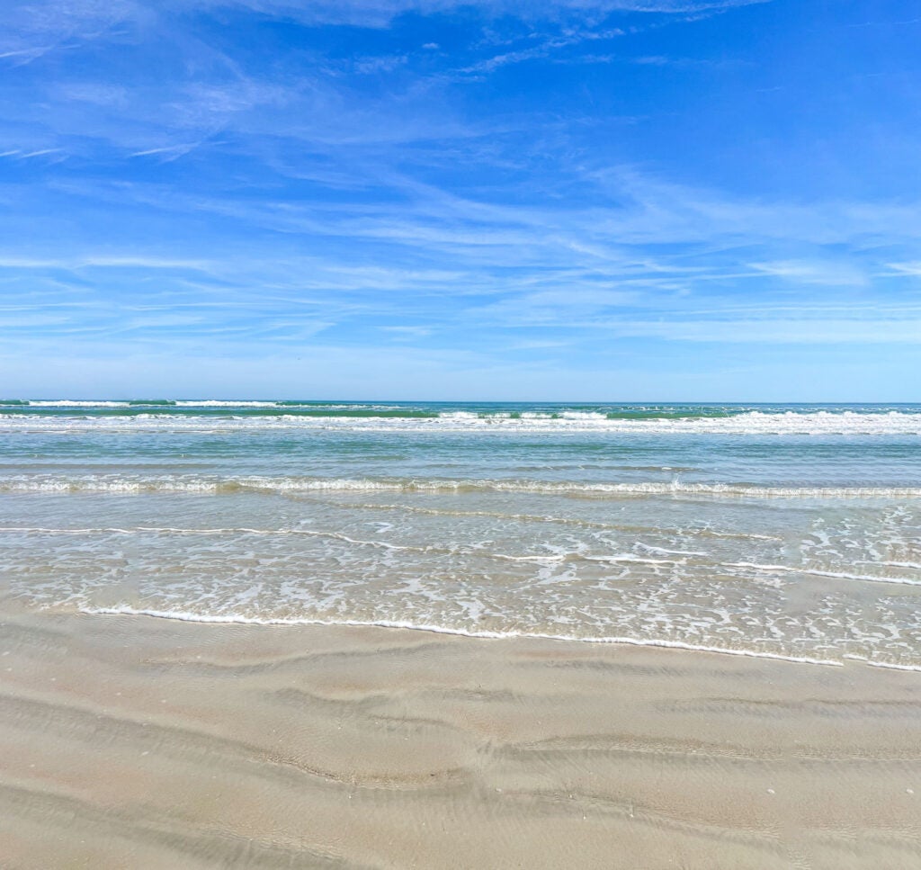 gorgeous beach with blue sky, water reaching up the sand