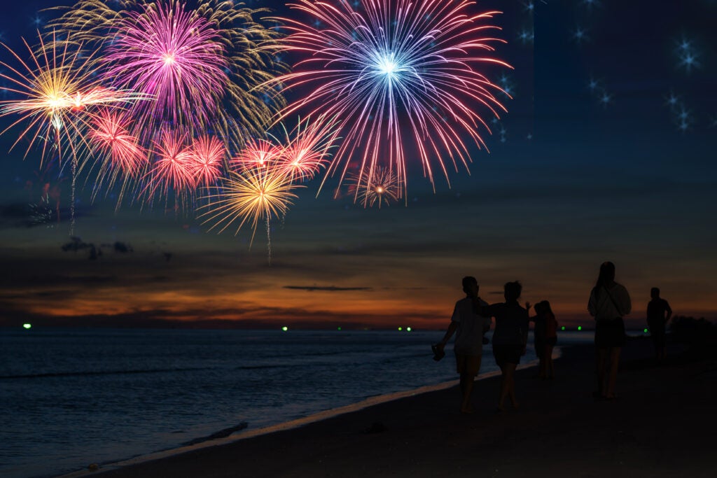 fireworks over beach with family walking along beach